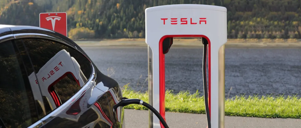 Tesla charging at a Supercharger beside a lake